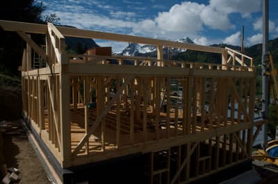 Architectural project - mountain view, scenic backdrop, construction elements, rustic setting, natural elements, green construction, scenic location, timber home, outdoor scene, framework, wood, timber, timber frame, exposed structure, under construction, site work, outdoor construction, construction process, construction materials, building site, beige, wooden beams, timber construction, eco-friendly construction, open framework, residential construction, blue sky, wood structure, sustainable building, building foundation, outdoor building, woodwork, natural landscape, green landscape, wood frame, nature-inspired, rural setting, nature integration, scenic architecture, architectural process
