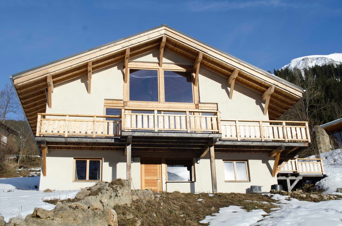 Architectural project - beige facade, mountain retreat, rustic elegance, vernacular style, open balcony, eco lodge, wooden balcony, idyllic setting, natural materials, wood, timber, warm tones, neutral tones, exposed beams, beige, brown, timber facade, timber beams, rustic charm, serene atmosphere, cozy retreat, scenic view, countryside home, outdoor view, plaster, rustic cabin, earthy tones, sloped roof, traditional architecture, natural aesthetics, environmentally friendly, gable roof, nature escape, sustainable cabin, peaceful vibe, wooden facade, vacation home, plaster walls, wooden structure, natural surroundings
