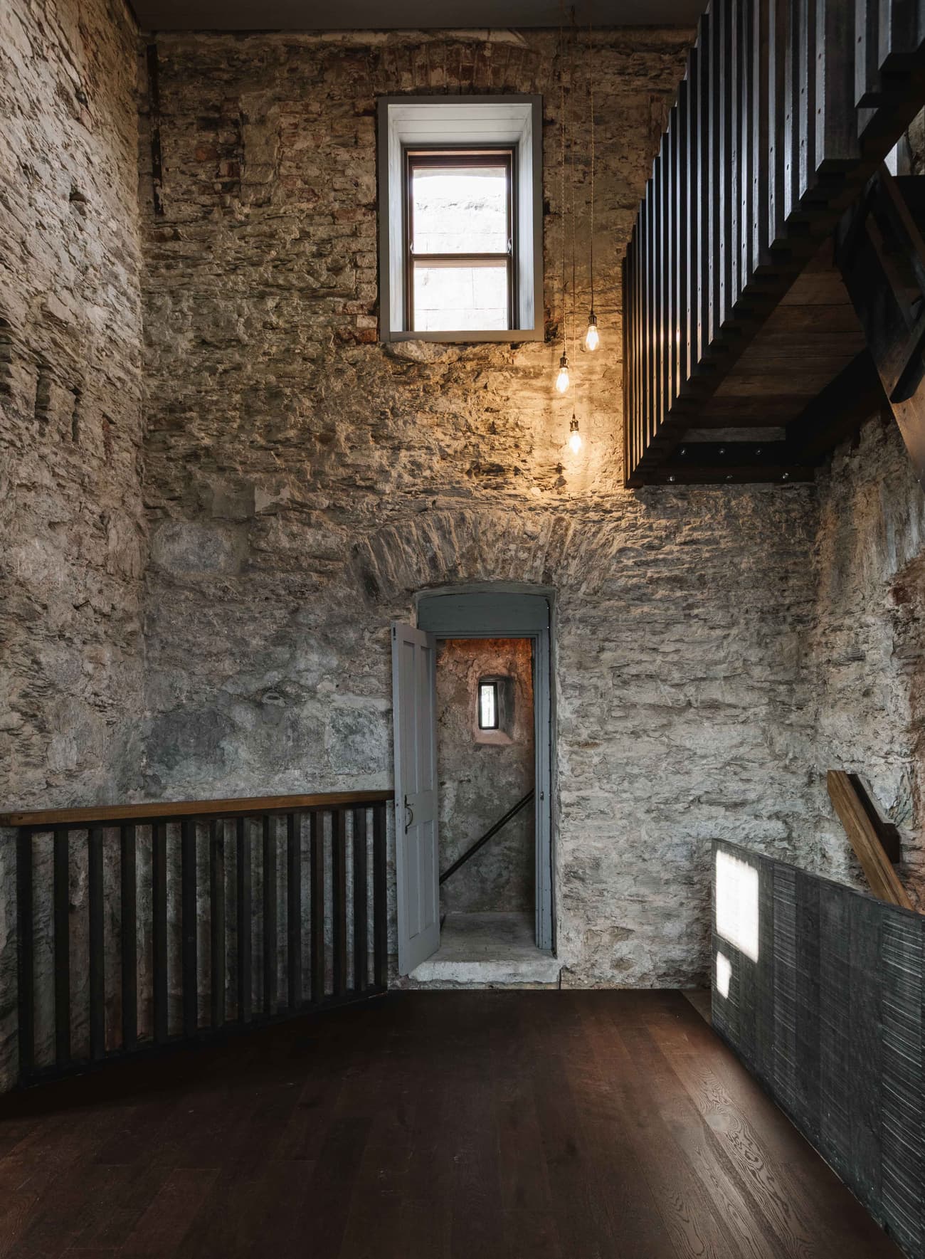 Architectural project - industrial interior, loft style, rugged finish, vintage vibe, exposed brick, pendant lights, reclaimed wood, historic building, historic charm, moody atmosphere, natural materials, architectural detail, sustainable materials, wood, warm tones, grey, neutral tones, brown, eco friendly, rustic modern, wooden floor, adaptive reuse, cozy space, industrial chic, textured wall, stone, cozy nook, living area, minimalist decor, stone wall, rustic wall, heritage architecture, residential space, timber railing, interior design, warm lighting, staircase, urban style, brick texture, stone texture