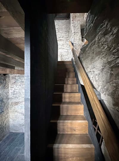 Architectural project - interior stair, exposed stone, heritage design, rustic interior, muted colors, historic building, vintage feel, atmospheric space, rustic stairs, timber stairs, moody atmosphere, intimate space, architectural detail, wood, timber, raw materials, grey tones, warm tones, natural tones, grey, beige, brown, rustic vibe, rustic modern, rustic charm, industrial touch, cozy space, natural finish, warm wood, plaster wall, stone, plaster, earthy tones, stone wall, cozy corner, textured walls, renovation, dark tones, stone texture, remodel