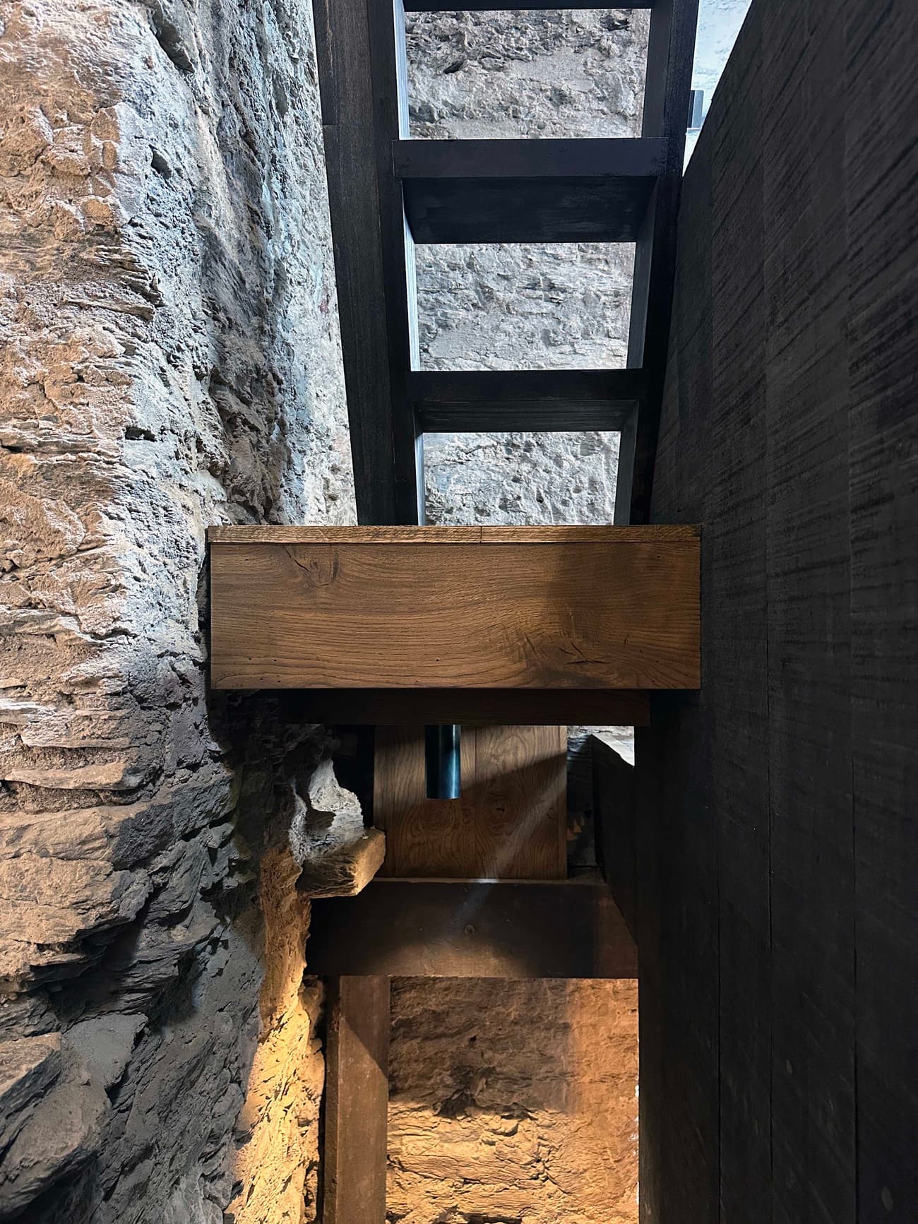 Architectural project - interior stair, exposed stone, wooden steps, heritage conservation, medieval style, vintage charm, wood stair, rugged look, cozy interior, intimate space, natural materials, architectural detail, wood, timber, raw materials, grey tones, natural light, sustainable design, reclaimed materials, warm tones, beige, brown, compact space, timber beams, rustic charm, industrial touch, minimalist design, structural wood, cozy vibe, textured wall, stone, earthy tones, rustic design, stone wall, heritage building, grey stone, eco architecture, architectural contrast, organic textures, dark wood, artisan craft, timber stair, stone texture
