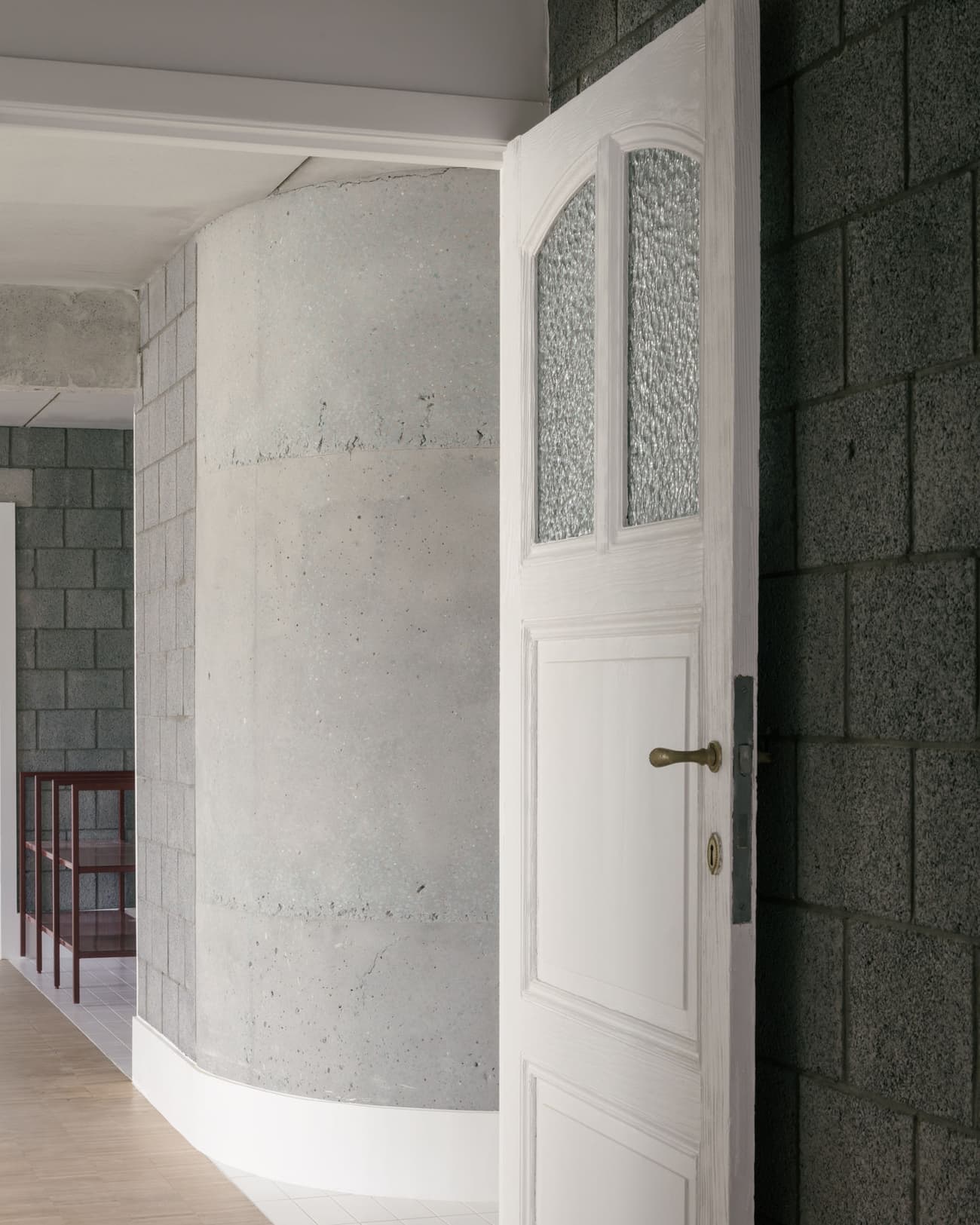 Architectural project - passageway, exposed materials, simple aesthetic, urban aesthetic, light wood floor, block wall, interior detail, white door, vintage handle, privacy, structured look, contemporary vibes, subtle contrast, refined elegance, structural expression, understated design, privacy design, design contrast, texture, block, architectural detail, grey tones, raw materials, grey, neutral tones, concrete, industrial style, modern design, architectural texture, neutral palette, construction detail, clean lines, white, textured wall, minimalist space, modern home, sleek design, calm atmosphere, clean design, hallway, concrete wall, minimalist interior, residential interior, urban style, entryway