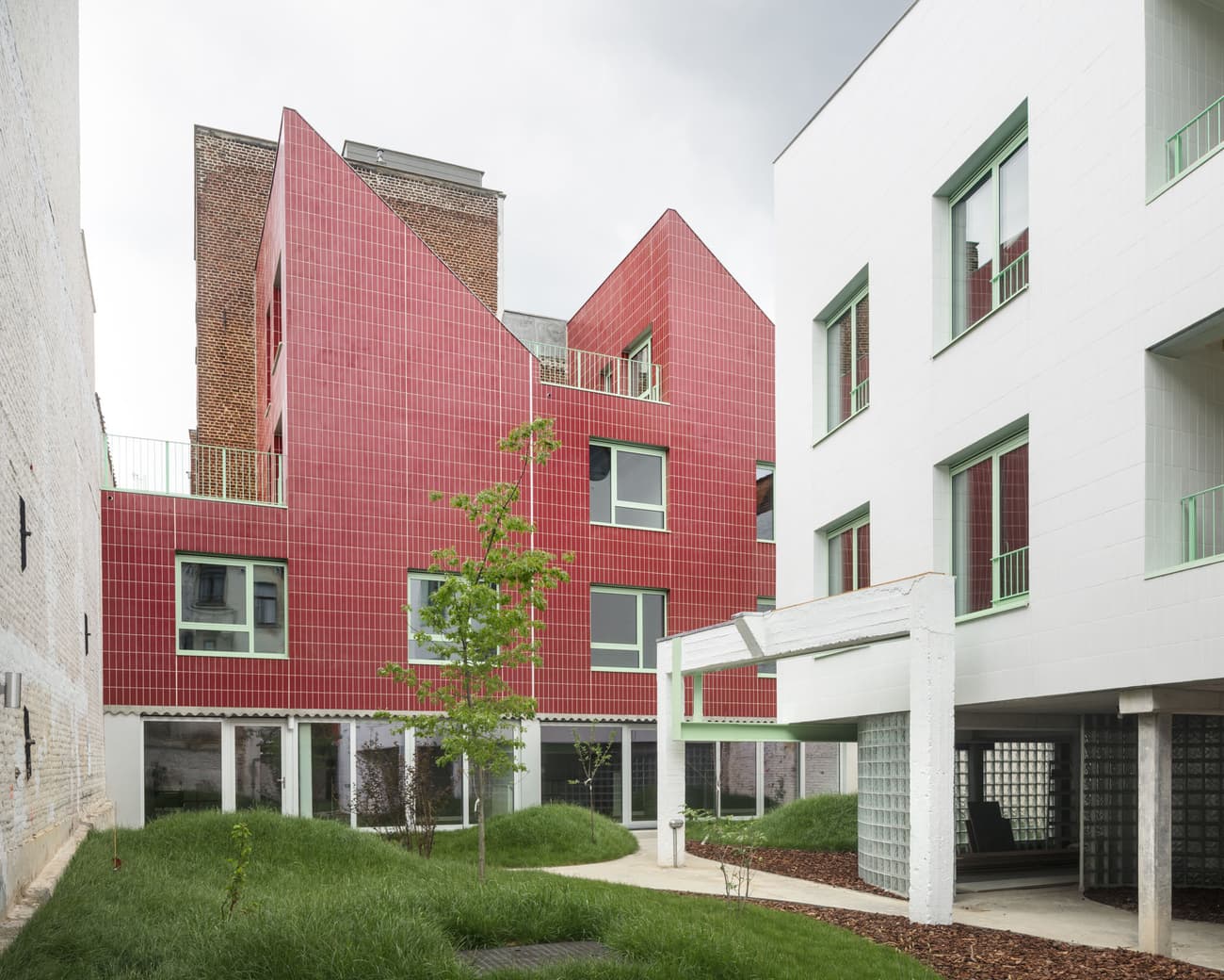 Architectural project - residential complex, colorful facade, angular roof, urban renewal, vibrant exterior, red tiles, geometric architecture, green courtyard, terracotta finish, city view, light green accents, modern community, urban redevelopment, building contrast, urban habitat, eco-friendly design, sustainable materials, cityscape, natural light, outdoor area, green, modern design, urban oasis, minimalist architecture, sustainable building, passive house, modern facade, large windows, energy efficient design, white, terracotta, brick, outdoor connection, sleek design, architectural harmony, innovative architecture, architectural contrast, white tiles, ceramic, ceramic tiles, contemporary living, city dwelling, urban living, urban housing, brick texture, red, communal space