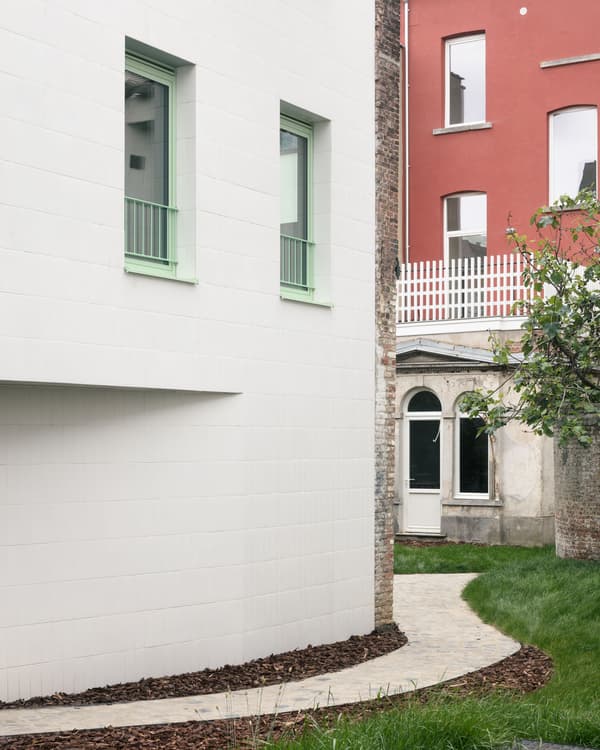 Architectural project - green accents, urban dwelling, contrasting colors, red building, residential exterior, curved path, townhouse design, sleek architecture, tiled facade, light green windows, urban courtyard, paving stones, crisp design, sustainable city, refined aesthetic, minimal design, urban setting, city living, outdoor space, eco design, outdoor area, green, neutral tones, city architecture, compact space, bright colors, geometric design, light tones, modern facade, clean lines, white facade, white, brick, residential architecture, minimalist exterior, modern home, garden path, green lawn, modern living, contemporary vibe, urban garden, architectural contrast, white tiles, tiles, urban exterior, red