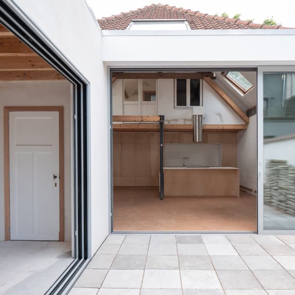 Architectural project - modern renovation, home extension, attic conversion, airy room, wood details, brick tiles, integrated kitchen, wood, timber, natural light, sustainable design, glass, warm tones, grey, neutral tones, exposed beams, beige, concrete, light wood, daylight optimization, compact space, wood beams, neutral palette, minimalist design, glass doors, multifunctional, Scandinavian vibe, timber elements, passive house, contemporary home, white walls, indoor outdoor, white, Nordic style, energy efficient, cozy kitchen, open layout, open plan, terracotta, bright space, sliding doors, residential, home, eco renovation, terracotta floor, skylight, urban living