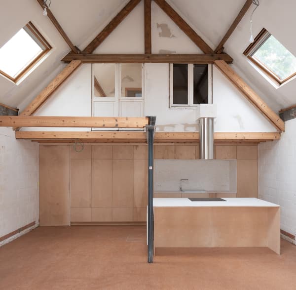 Architectural project - plywood walls, skylights, attic renovation, loft conversion, renovation project, multipurpose space, warm floor, architectural detail, sustainable materials, natural light, passive design, sustainable design, neutral tones, exposed beams, daylight, beige, brown, truss structure, light wood, timber beams, rustic modern, industrial touch, Scandinavian style, minimalist design, wood floor, wood panels, modern rustic, clean lines, white, Nordic design, eco friendly home, small space, warm ambiance, open plan, earthy tones, bright interior, functional layout, kitchen island, compact kitchen, plaster walls, modern living, cozy home, eco renovation, vaulted ceiling