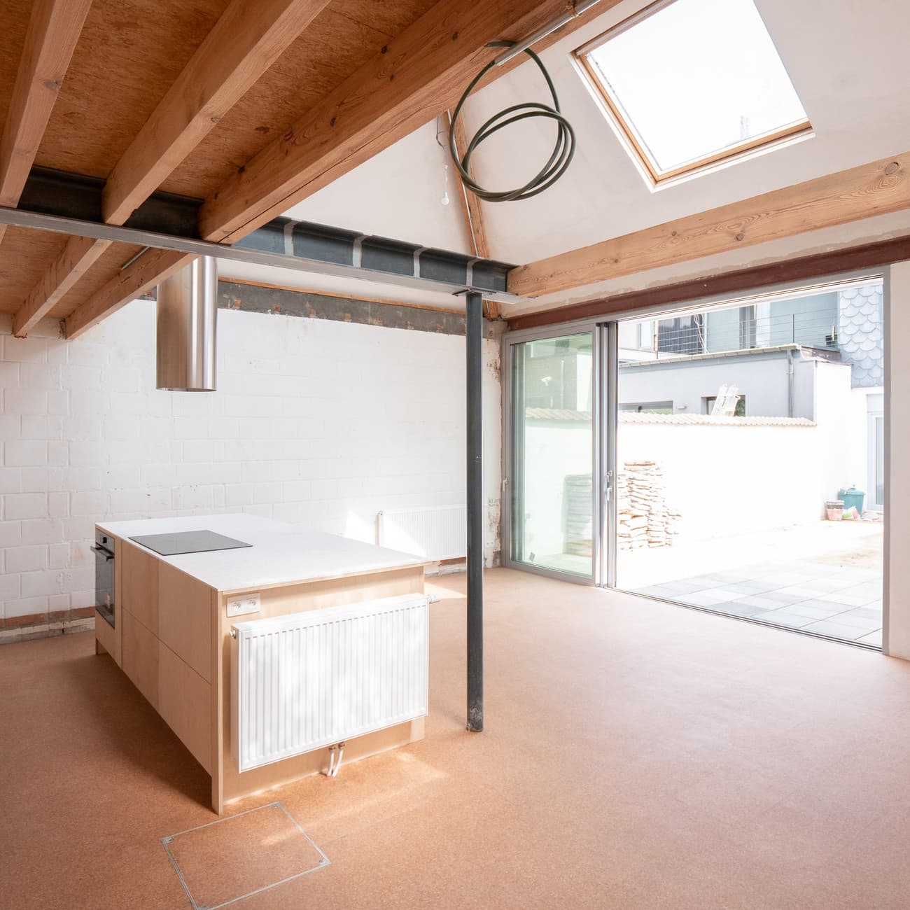 Architectural project - loft kitchen, modern renovation, streamlined design, courtyard view, cork, warm floor, cozy interior, warm interior, natural materials, wood, timber, steel, natural light, glass, warm tones, exposed beams, daylight, wooden ceiling, industrial vibe, beige, light wood, multifunctional space, eco friendly, wood beams, timber beams, industrial touch, light brown, neutral palette, glass doors, low carbon, sustainable home, passive house, contemporary home, white walls, light filled, indoor outdoor, white, energy efficient, plaster, timber ceiling, bright kitchen, casual living, open layout, open plan, inviting space, earthy tones, minimalist kitchen, modern kitchen, sleek design, kitchen island, sliding doors, plaster walls, open shelving, skylight