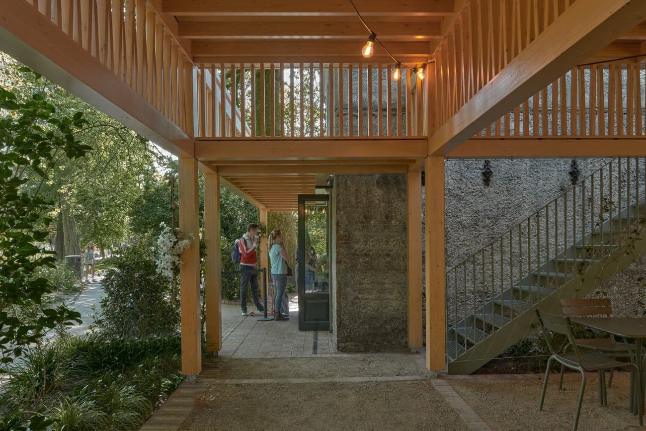 Architectural project - gathering place, cozy ambiance, rustic furniture, landscaping, timber pavilion, rustic stairs, informal meeting, intimate space, natural materials, eco-friendly design, wood, timber, natural light, sustainable design, warm tones, community space, green, exposed beams, daylight, beige, brown, concrete, open structure, wooden beams, honey wood, natural textures, retreat space, peaceful setting, eco materials, casual space, biophilic design, indoor outdoor, timber cladding, inviting space, social gathering, earthy tones, warm atmosphere, garden design, green design, wooden stairs, wooden furniture, green space, natural garden