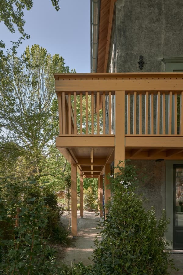 Architectural project - nature vibes, exterior facade, countryside charm, plant-filled, timber posts, relaxing atmosphere, peaceful space, backyard view, outdoor facade, natural materials, serene environment, raw materials, natural light, outdoor living, warm tones, eco design, exposed structure, neutral tones, daylight, light wood, natural wood, eco friendly, rural architecture, honey wood, green architecture, sustainable home, countryside home, textured wall, plaster wall, rustic style, earthy tones, garden view, green design, open air, countryside living, rustic home, inviting exterior, warm exterior, outdoor deck, lush greenery, foliage, cozy home, timber railing, soft colors, architectural harmony, connection to nature