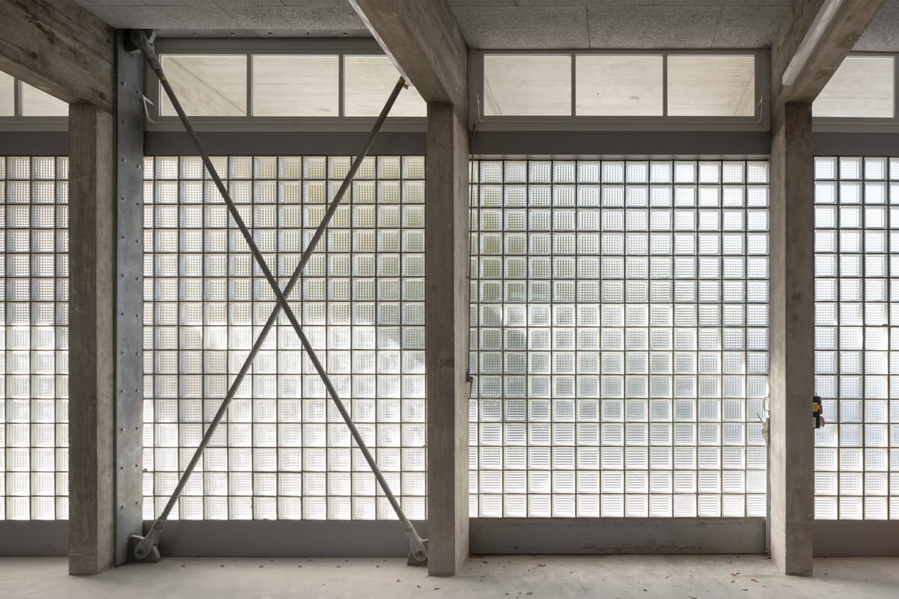 Architectural project - repetitive elements, raw concrete, concrete structure, industrial facade, commercial space, exposed framework, textured concrete, modernist design, grid pattern, geometric patterns, glass block wall, steel brace, brutalist touch, structural transparency, facade transparency, light-filled design, streamlined look, engineered aesthetics, retro modern, contemporary industrial, facade elements, architectural detail, grey tones, steel, natural light, privacy screen, glass, modular design, industrial aesthetic, contemporary architecture, grey, neutral tones, daylight, industrial vibe, concrete, building facade, minimalist facade, functional design, open structure, neutral palette, urban design, modern facade, clean lines, large windows, white, airy space, building envelope