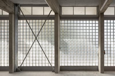 Architectural project - repetitive elements, raw concrete, concrete structure, industrial facade, commercial space, exposed framework, textured concrete, modernist design, grid pattern, geometric patterns, glass block wall, steel brace, brutalist touch, structural transparency, facade transparency, light-filled design, streamlined look, engineered aesthetics, retro modern, contemporary industrial, facade elements, architectural detail, grey tones, steel, natural light, privacy screen, glass, modular design, industrial aesthetic, contemporary architecture, grey, neutral tones, daylight, industrial vibe, concrete, building facade, minimalist facade, functional design, open structure, neutral palette, urban design, modern facade, clean lines, large windows, white, airy space, building envelope