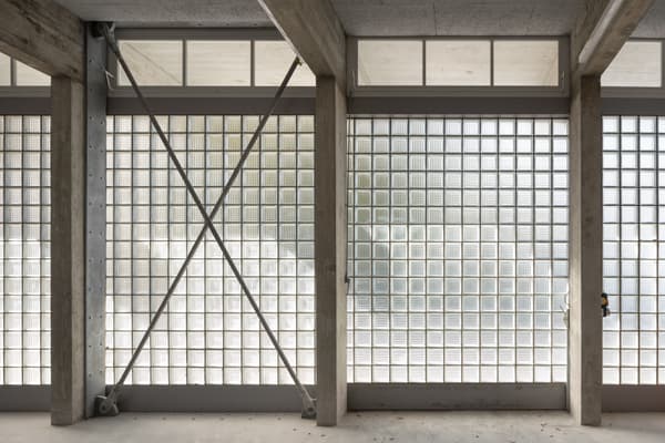 Architectural project - repetitive elements, raw concrete, concrete structure, industrial facade, commercial space, exposed framework, textured concrete, modernist design, grid pattern, geometric patterns, glass block wall, steel brace, brutalist touch, structural transparency, facade transparency, light-filled design, streamlined look, engineered aesthetics, retro modern, contemporary industrial, facade elements, architectural detail, grey tones, steel, natural light, privacy screen, glass, modular design, industrial aesthetic, contemporary architecture, grey, neutral tones, daylight, industrial vibe, concrete, building facade, minimalist facade, functional design, open structure, neutral palette, urban design, modern facade, clean lines, large windows, white, airy space, building envelope