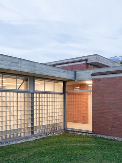 Architectural project - linear design, concrete finish, transitional space, roof terrace, open courtyard, rectilinear form, glass block, clerestory windows, exterior courtyard, masonry wall, minimalist landscaping, hardscape, connecting spaces, exterior modern, grey tones, natural light, outdoor living, sustainable design, glass, modular design, eco design, grey, green, industrial vibe, concrete, functional design, flat roof, facade detail, minimalist vibe, contemporary design, passive house, clean lines, large windows, indoor outdoor, modern architecture, energy efficient, brick, brick facade, red brick, garden view, minimalist exterior, residential building, concrete elements, green space, urban garden, architectural rhythm, daylighting, low carbon architecture, geometric form, urban living, urban style, red, city style