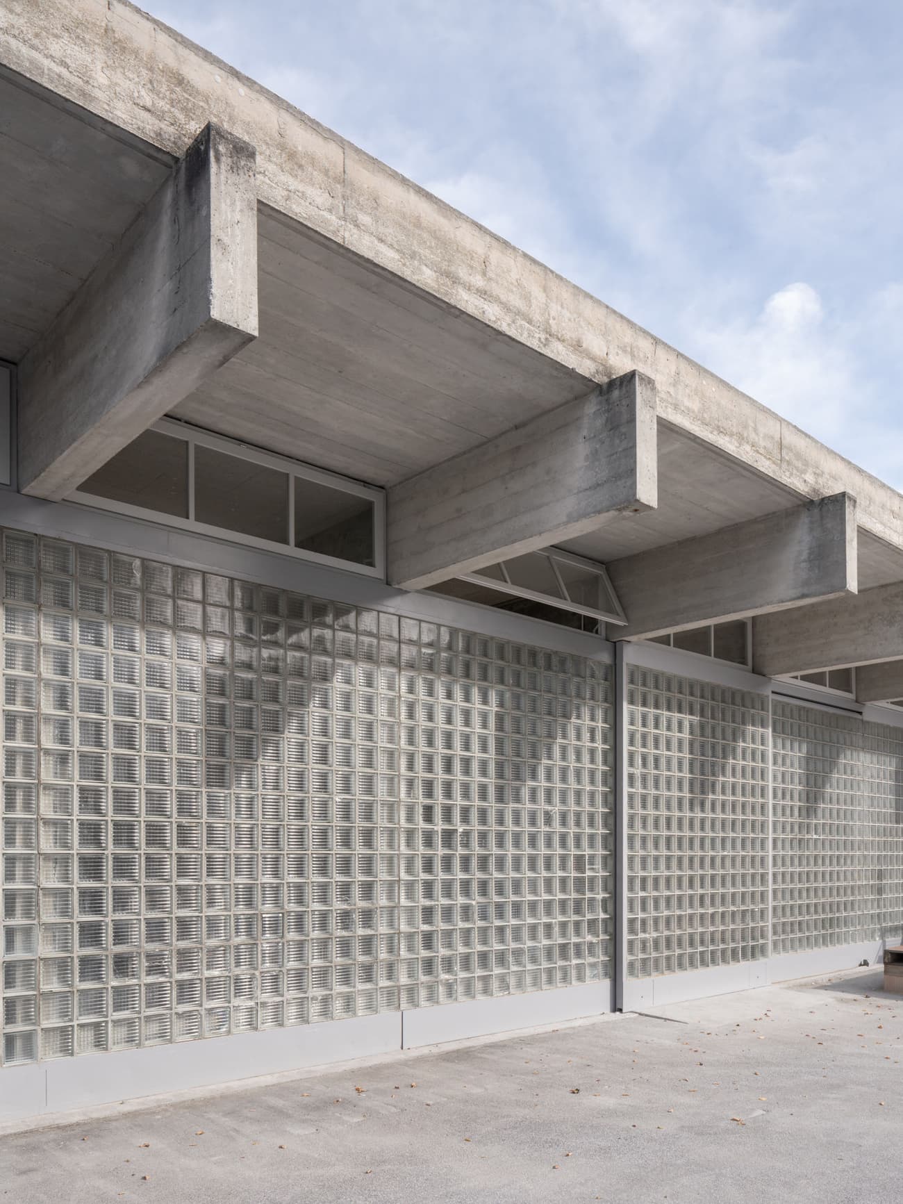 Architectural project - exposed concrete, light grey, industrial facade, modern industrial, low maintenance, concrete facade, robust structure, structural expression, atmospheric light, modernist architecture, glass block, brutalist style, glass block wall, grid texture, utilitarian aesthetic, functional simplicity, reinforced concrete, architectural detail, eco-friendly design, grey tones, industrial design, raw materials, outdoor space, passive design, industrial aesthetic, contemporary architecture, daylight, industrial vibe, exterior design, geometric pattern, simple design, minimalist style, neutral palette, translucent wall, urban design, architecture detail, structural beams, durable materials, sustainable material, sleek design, modern exterior, public building, functional facade, urban facade, industrial modern