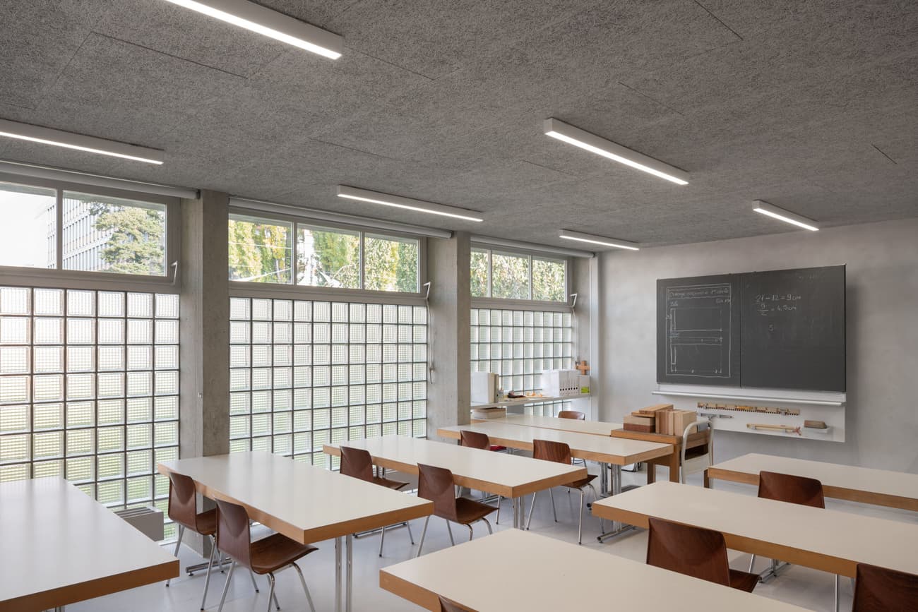 Architectural project - grid windows, minimalist furniture, timber desk, classroom, educational, school room, modern classroom, glass block windows, wood desk, sleek chairs, student chairs, teaching board, chalkboard, blackboard, white desks, brown chairs, study environment, academic setting, low energy, minimalist learning, natural light, passive design, sustainable design, modern vibe, neutral tones, daylight, light wood, functional design, daylight optimization, eco friendly, minimalist vibe, contemporary design, neutral palette, minimalist design, neutral colors, clean lines, large windows, plaster wall, beige tones, open plan, study area, bright interior, simple decor, efficient layout, open space, educational space, learning space, wooden furniture, modern education, learning environment, concrete wall, bright room