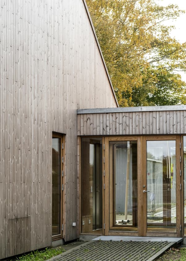Architectural project - low carbon home, natural materials, wood, timber, outdoor space, natural light, sustainable design, yellow, glass, warm tones, sustainable architecture, grey, green, daylight, beige, brown, timber facade, minimalist facade, eco friendly, timber construction, Scandinavian style, neutral palette, exterior, biophilic design, eco home, passive house, contemporary home, landscape integration, wood cladding, Nordic design, harmonious design, modern architecture, energy efficient, inviting entrance, compact design, wood texture, earthy tones, garden view, eco architecture, residential building, seamless integration, home design, vertical slats, modern exterior, wooden building