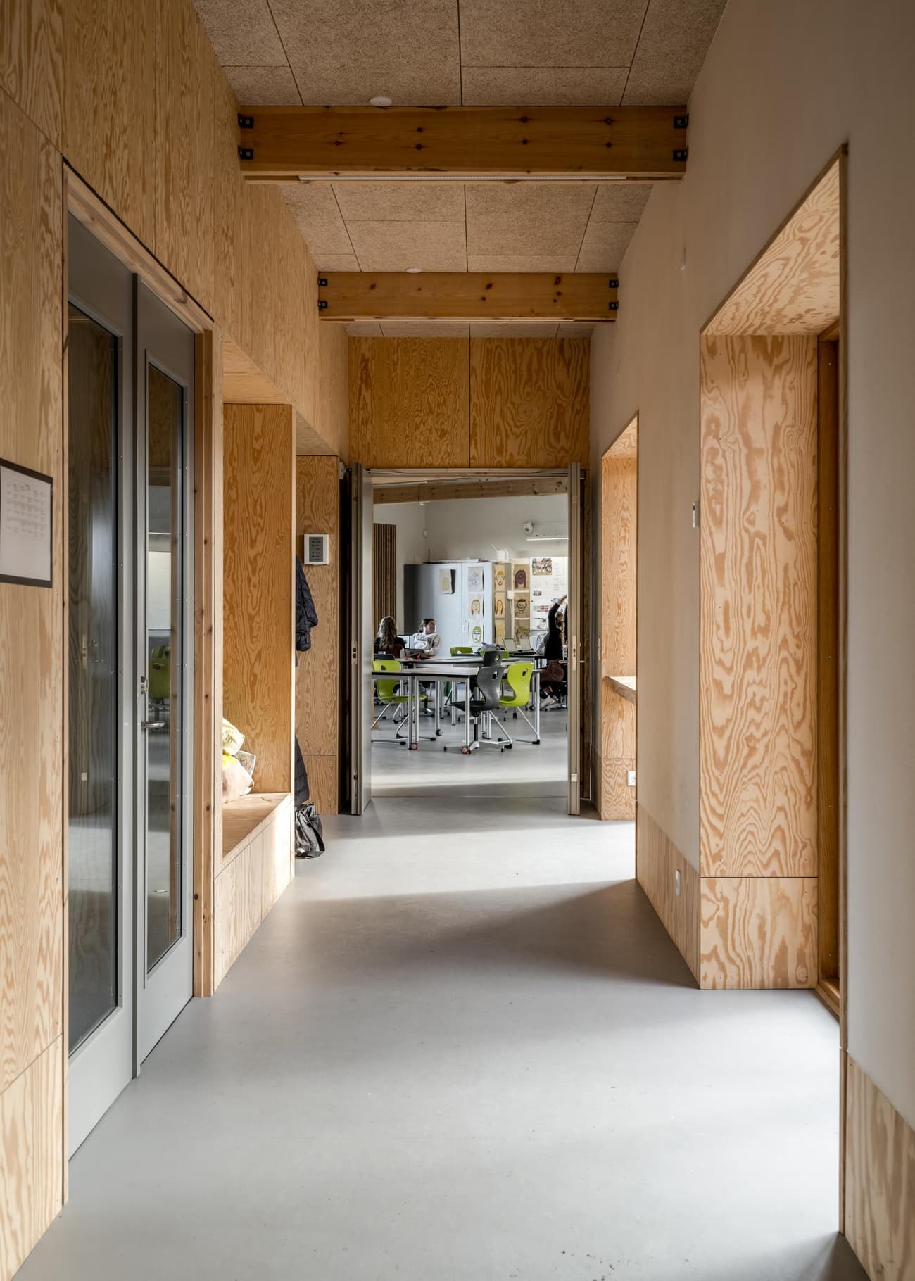 Architectural project - sustainability, ceiling detail, open connection, open door, polished concrete, plywood construction, indoor space, natural materials, eco-friendly design, raw materials, natural light, inviting atmosphere, eco-conscious, sustainable design, modular design, community space, neutral tones, exposed beams, functional space, light wood, natural wood, Scandinavian influence, timber construction, honey wood, contemporary design, minimalist design, structural beams, durable materials, passive house, clean lines, Nordic style, beige tones, warm ambiance, timber interior, green design, bright space, concrete floor, educational space, simple lines, educational building, public building, learning environment, welcoming space, modern school, corridor, practical design, interior architecture, wooden paneling, wood interior
