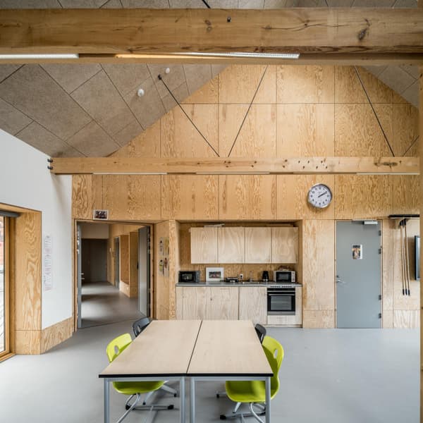 Architectural project - raw finishes, flexible space, light grey, meeting room, collaborative space, plywood walls, cozy interior, natural materials, eco-friendly design, wood, timber, sustainable design, warm tones, contemporary style, grey, exposed beams, daylight, plywood, gathering space, beige, light wood, low carbon design, engineered wood, modern design, natural textures, minimalist style, neutral palette, casual seating, social space, community center, yellow accents, event venue, bright colors, eco building, structural wood, green architecture, Nordic style, timber interior, open layout, inviting space, warm atmosphere, Scandinavian design, bright interior, functional layout, wood ceiling, educational space, public building, wood paneling, timber paneling, practical design, simple furniture, wood interior