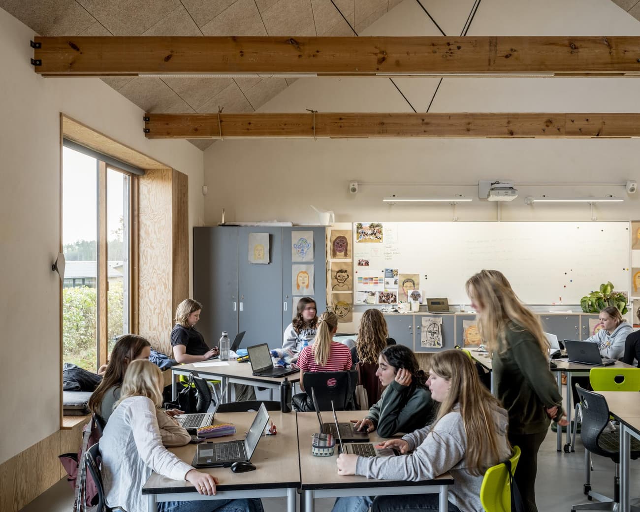 Architectural project - flexible space, green chairs, study room, classroom, modern classroom, chalkboard, academic setting, modular furniture, minimal design, warm interior, wood, timber, natural light, inviting atmosphere, sustainable design, eco design, grey, exposed beams, daylight, beige, light wood, wood beams, timber beams, Scandinavian style, neutral palette, interactive space, large windows, Nordic design, airy space, timber interior, open plan, eco friendly space, multifunctional room, educational space, learning space, educational setting, wood interior