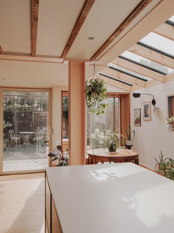 Architectural project - indoor garden, glass roof, plant decor, sunlit space, dining nook, peach walls, hanging plants, warm interior, natural materials, pastel tones, timber, relaxed vibe, natural light, sustainable design, glass, warm tones, green, daylight, beige, light wood, timber beams, minimalist style, relaxed atmosphere, soft textures, modern rustic, biophilic design, eco home, eco friendly home, wood frame, open layout, open plan, inviting space, casual dining, residential design, cozy corner, garden view, earthy palette, comfortable living, interior space, skylight, home renovation, indoor outdoor flow, bright home