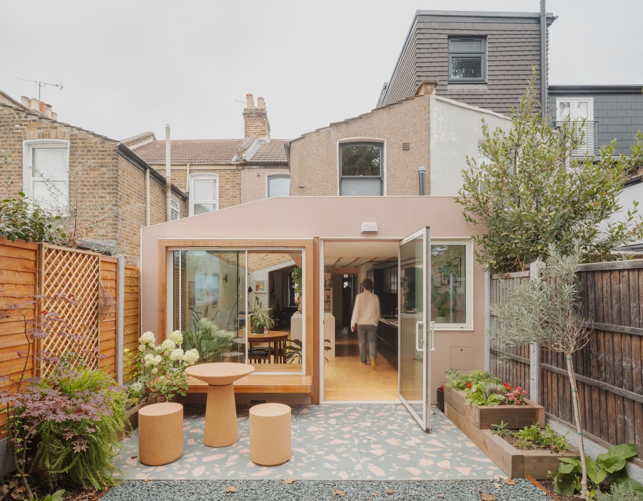 Architectural project - terrace, pink facade, urban renewal, patio space, brick house, modern extension, contemporary addition, garden furniture, landscaped garden, home addition, terrazzo floor, garden room, timber fence, exterior seating, pastel pink, pastel tones, wood, natural light, outdoor living, sustainable design, glass, warm tones, neutral tones, daylight, concrete, eco friendly, urban oasis, outdoor seating, open facade, brick, residential design, backyard retreat, garden view, residential garden, seamless indoor outdoor, modern living, urban garden, home renovation, sliding glass doors