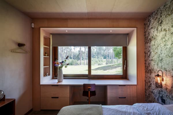 Architectural project - wood wall, modern lamp, plywood walls, ceiling light, bedroom, wooden desk, compact room, writing desk, built-in desk, peaceful room, flower vase, wall lamp, bedside light, wooden chair, desk chair, relaxation space, natural materials, wood, timber, natural light, sustainable design, glass, warm tones, eco design, green, functional space, plywood, beige, brown, modern design, rustic modern, calm ambiance, private retreat, Scandinavian style, minimalist style, neutral palette, workspace, modern rustic, biophilic design, passive house, natural ventilation, nature view, white, cozy vibe, Nordic style, large window, textured wall, stone, minimalist decor, earthy tones, nature-inspired, stone wall, relaxing space, garden view, home office, simple decor, timber wall, cozy bedroom, indoor plant