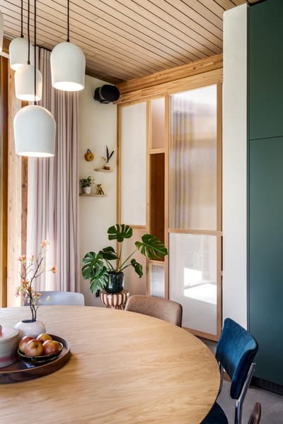 Architectural project - home decor, organic elements, modern dining, family dining, home dining, round table, room divider, potted plant, pendant lights, green accent, hanging lamps, monstera plant, partition screen, curtain wall, dining space, pastel, natural materials, soft lighting, sustainable materials, pastel tones, wood, timber, fabric, relaxed vibe, natural light, glass, eco design, green, neutral tones, beige, light wood, Scandinavian style, minimalist design, cozy space, white, inviting home, Nordic style, timber ceiling, open layout, wooden table, warm atmosphere, casual dining, modern home, simple decor, earthy textures, wood ceiling, Japandi, indoor plants, contemporary living, frosted glass