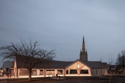 Architectural project - gray, integration with nature, outdoor lighting, evening glow, large openings, civic building, light gray, wood, timber, outdoor space, sustainable design, contemporary architecture, urban landscape, neutral tones, timber structure, multi-use space, beige, brown, concrete, steel columns, eco friendly, minimalist design, eco materials, community hub, gathering area, community center, open facade, wood construction, geometric design, low carbon, modern facade, gable roof, public building, warm lighting