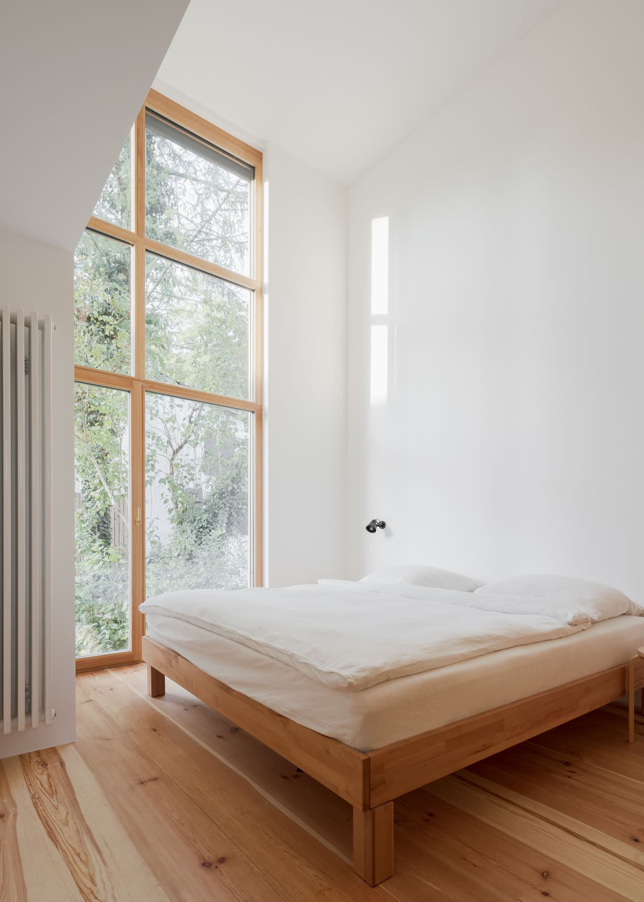 Architectural project - indoor greenery, modern bedroom, simple bedroom, Japandi influence, bedroom design, simple bed, wooden bed frame, natural views, tranquil bedroom, spacious bedroom, open feel, light color palette, soft lighting, eco-friendly design, sustainable materials, wood, timber, natural light, glass, neutral tones, beige, light wood, calm ambiance, timber floor, minimalist design, serene space, Scandinavian vibe, warm wood, wood floor, passive house, clean lines, white walls, white, large window, peaceful retreat, cozy corner, residential space, modern style, home interior, airy atmosphere, understated elegance, modern interior, minimalist bedroom, bright room