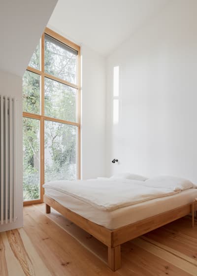 Architectural project - indoor greenery, modern bedroom, simple bedroom, Japandi influence, bedroom design, simple bed, wooden bed frame, natural views, tranquil bedroom, spacious bedroom, open feel, light color palette, soft lighting, eco-friendly design, sustainable materials, wood, timber, natural light, glass, neutral tones, beige, light wood, calm ambiance, timber floor, minimalist design, serene space, Scandinavian vibe, warm wood, wood floor, passive house, clean lines, white walls, white, large window, peaceful retreat, cozy corner, residential space, modern style, home interior, airy atmosphere, understated elegance, modern interior, minimalist bedroom, bright room