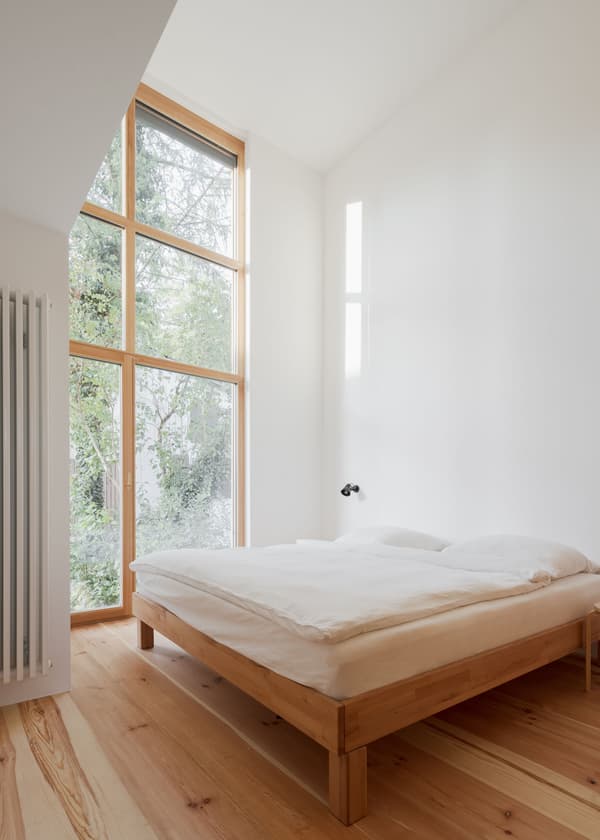 Architectural project - indoor greenery, modern bedroom, simple bedroom, Japandi influence, bedroom design, simple bed, wooden bed frame, natural views, tranquil bedroom, spacious bedroom, open feel, light color palette, soft lighting, eco-friendly design, sustainable materials, wood, timber, natural light, glass, neutral tones, beige, light wood, calm ambiance, timber floor, minimalist design, serene space, Scandinavian vibe, warm wood, wood floor, passive house, clean lines, white walls, white, large window, peaceful retreat, cozy corner, residential space, modern style, home interior, airy atmosphere, understated elegance, modern interior, minimalist bedroom, bright room