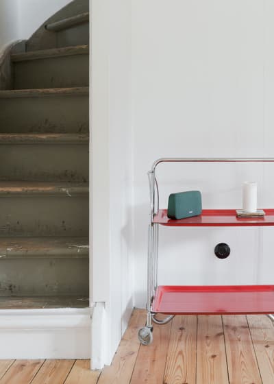 Architectural project - retro vibe, vintage touch, subtle design, subtle colors, wooden steps, painted stairs, metal bar cart, red bar cart, compact layout, home accessory, plank floor, natural wood floor, vinyl records, stylish storage, casual home, everyday living, olive green, wood, metal, warm tones, neutral tones, beige, functional design, Scandinavian style, wooden floor, relaxed atmosphere, clean lines, white walls, Nordic style, small space, inviting space, cozy corner, modern home, simple decor, cozy home, understated elegance, practical design, minimalist interior, staircase, urban living, red