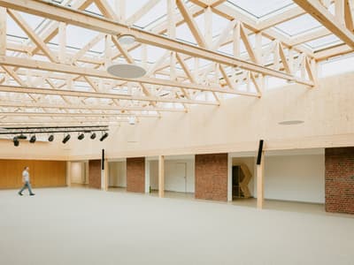 Architectural project - flexible space, passive lighting, brick wall, skylights, welcoming atmosphere, large space, multifunctional hall, acoustic panels, warm interior, eco-friendly design, sustainable materials, wood, timber, natural light, glass, warm tones, green building, contemporary style, neutral tones, daylight, gathering space, beige, brown, exposed trusses, timber trusses, light wood, natural wood, modern design, honey wood, neutral palette, community center, Nordic design, timber ceiling, open plan, inviting space, brick, brick facade, spacious interior, Scandinavian design, bright interior, wood ceiling, public building
