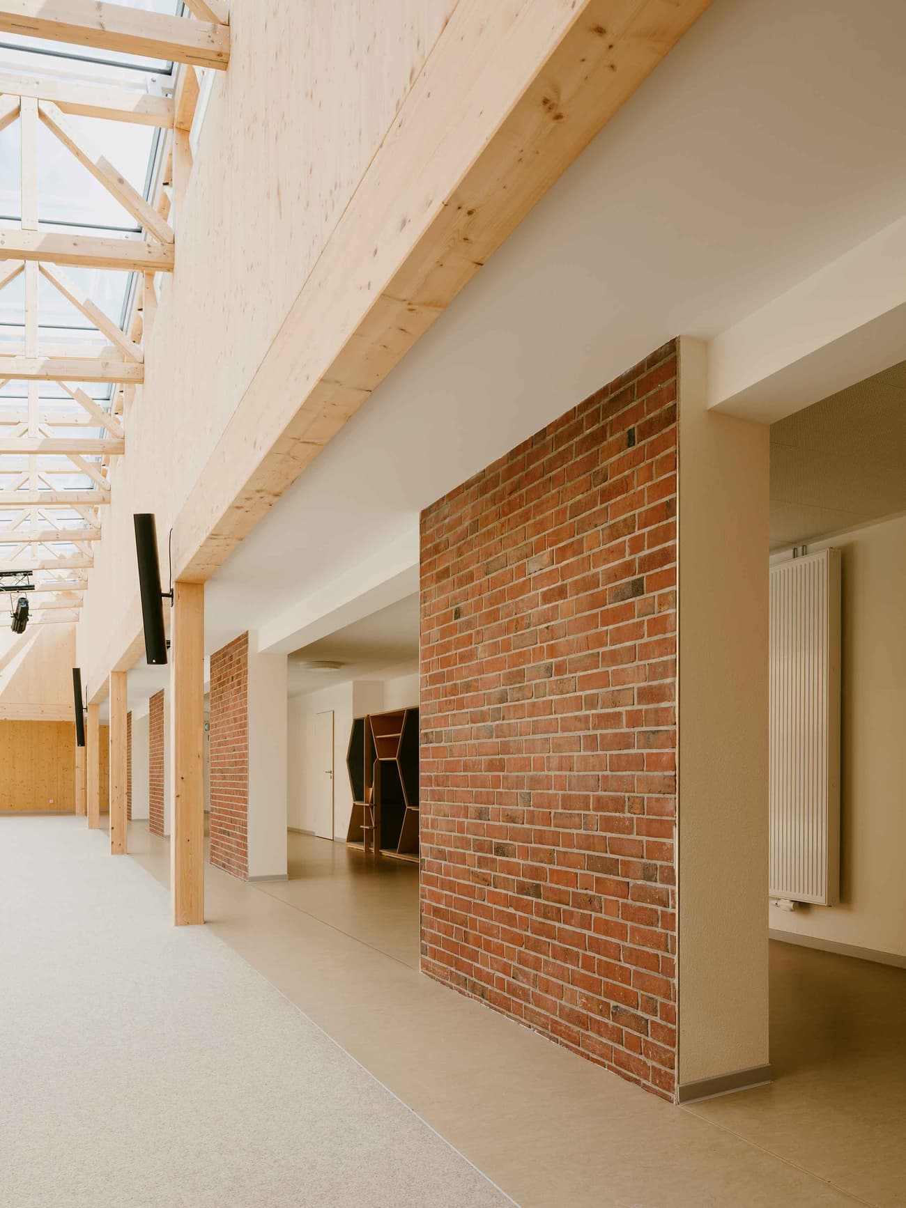 Architectural project - passageway, brick wall, indoor walkway, cozy interior, natural materials, wood, timber, natural light, sustainable design, glass, warm tones, modern vibe, neutral tones, exposed beams, functional space, beige, daylight optimization, contemporary design, industrial touch, Scandinavian style, light brown, minimalist design, adaptable space, natural ventilation, clean lines, Nordic design, modern architecture, timber ceiling, inviting space, brick, brick facade, eco-friendly building, bright interior, wood ceiling, structural elements, hallway, skylight, open corridor, communal space
