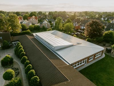 Architectural project - garden, brick exterior, educational facility, circular economy, brick walls, tile roof, classic style, window strip, suburban setting, eco-friendly design, outdoor space, natural light, passive design, warm tones, corrugated roof, green, neutral tones, ventilation, daylight, brown, functional design, flat roof, neutral palette, community hub, community center, sustainable building, biophilic design, metal roof, green landscape, large windows, white, earthy tones, pitched roof, traditional design, brick, brick facade, timeless design, fresh air, residential area, school building, green space, aerial view, clay tiles, modular elements