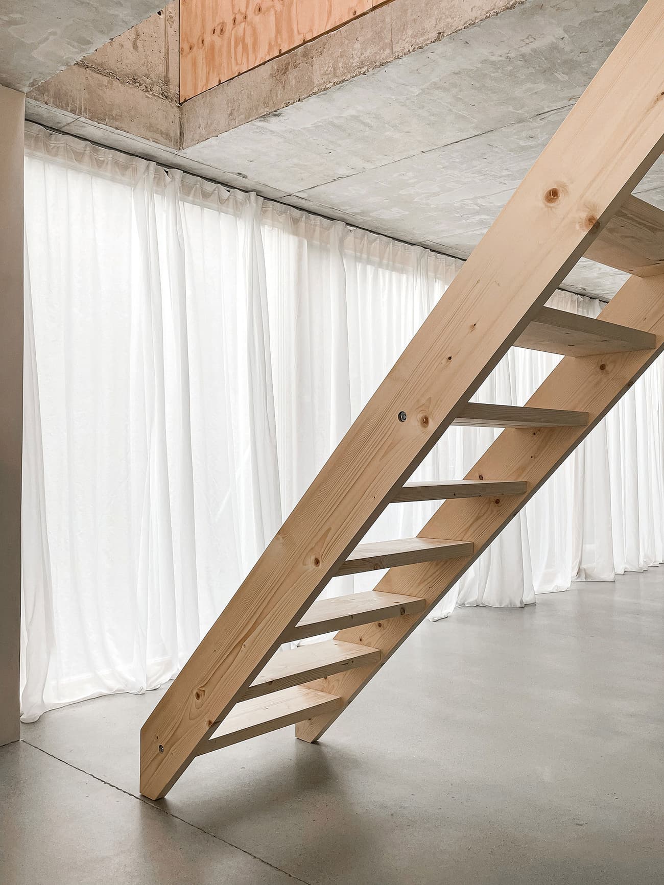 Architectural project - exposed concrete, smart design, loft style, airy interior, concrete ceiling, sheer curtains, structural simplicity, loft vibe, floating stairs, zen atmosphere, soft curtains, timber, raw materials, natural light, sustainable design, contemporary style, multifunctional area, neutral tones, functional space, plywood, beige, concrete, light wood, eco friendly, minimalist architecture, modern simplicity, neutral palette, calming space, minimalist design, urban design, clean lines, large windows, white, beige tones, open layout, bright space, compact living, nordic influence, concrete floor, wooden staircase, smooth surfaces, industrial space, timber steps