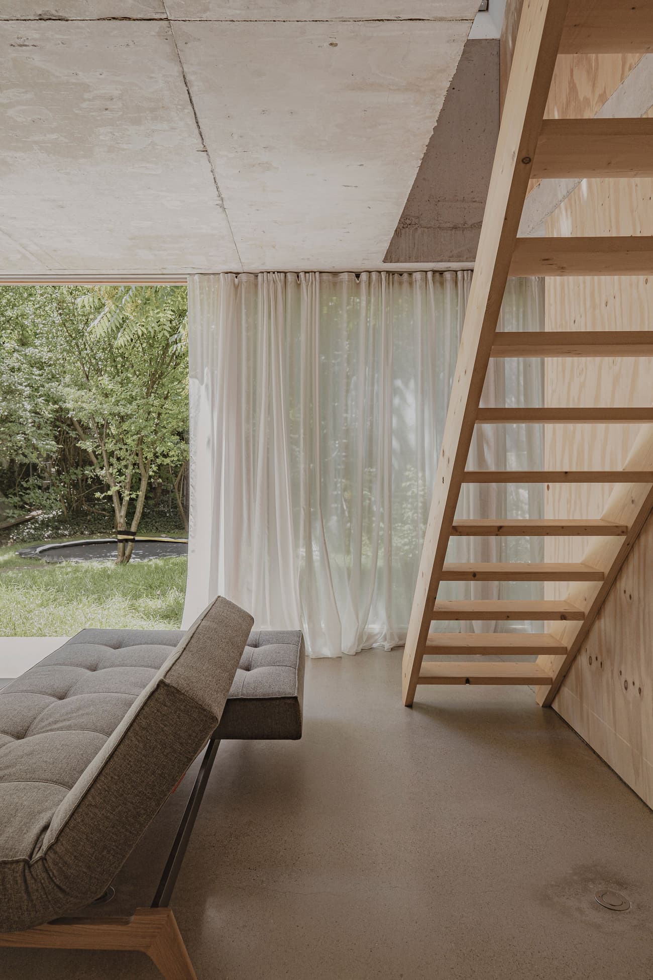 Architectural project - exposed concrete, timber shelf, polished concrete, tranquil home, seamless connection, natural light, sustainable design, warm tones, grey, plywood, beige, light wood, honey wood, Scandinavian style, neutral palette, minimalist design, soft textures, earth tones, biophilic design, passive house, contemporary home, clean lines, indoor outdoor, white, eco friendly home, green living, warm ambiance, airy space, open plan, nature-inspired, relaxing space, cozy corner, garden view, tranquil atmosphere, lounge chair, bright interior, modern furniture, modern living, wood ceiling, concrete floor, floor-to-ceiling window, minimal decor, greenery view, sliding door, glass wall, Japandi style, living space