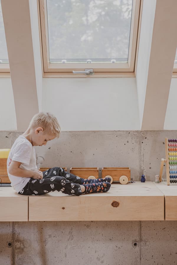 Architectural project - casual vibe, indoor setting, wooden toys, window seating, simple interior, minimal design, natural materials, wood, timber, natural light, sustainable design, warm tones, daylight, beige, concrete, light wood, compact space, minimalist style, relaxed atmosphere, Scandinavian vibe, eco-friendly materials, light tones, warm wood, white, Nordic design, small space, cozy nook, family home, modern home, home design, interior space, playful space, concrete wall, skylight, home renovation, residential interior, creative corner