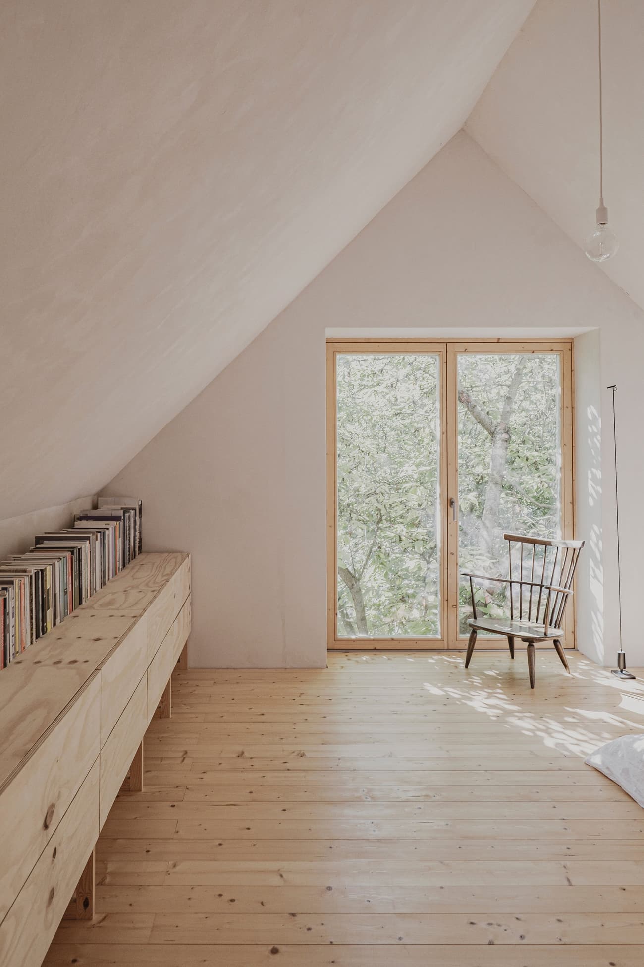 Architectural project - hygge, loft space, attic space, minimalist furniture, accent chair, minimal design, warm interior, natural materials, eco-friendly design, wood, timber, natural light, sustainable design, warm tones, beige, light wood, Scandinavian style, minimalist style, neutral palette, serene space, modern rustic, biophilic design, white walls, light filled, white, window view, Nordic style, airy space, relaxed setting, tranquil vibe, cozy corner, reading nook, reading area, home library, bright interior, calm atmosphere, simple decor, plaster walls, soft tones, wooden shelves, open shelving, Japandi, sloped ceiling