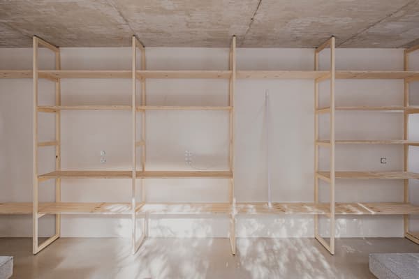 Architectural project - exposed concrete, urban loft, streamlined design, concrete ceiling, functional decor, indoor setting, storage solution, organized living, minimal vibe, sustainable materials, wood, raw materials, shadow play, natural tones, modular design, functional space, plywood, concrete, light wood, natural wood, Scandinavian style, neutral palette, eco-friendly materials, light tones, clean lines, Nordic design, beige tones, open shelves, interior, warm lighting, contemporary space, minimalist shelves, minimalist interior