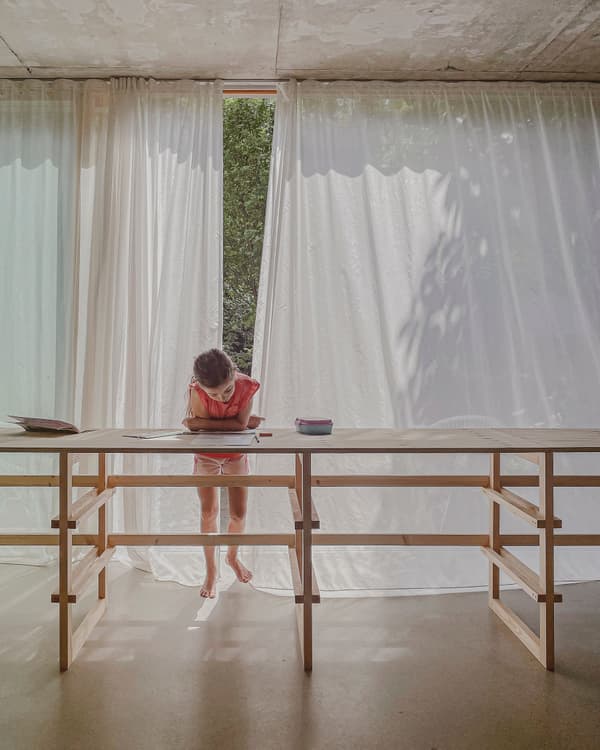 Architectural project - light-filled space, exposed concrete, peaceful environment, home sanctuary, simple table, calm vibe, sheer curtains, airy room, timber furniture, indoor space, timber, natural light, warm tones, eco design, neutral tones, beige, concrete, light wood, multifunctional space, daylight optimization, neutral palette, contemporary interior, minimalist design, serene space, relaxed atmosphere, soft textures, wood structure, sustainable home, natural ventilation, architectural simplicity, white, inviting interior, casual living, open plan, cozy corner, reading nook, home office, study area, concrete floor
