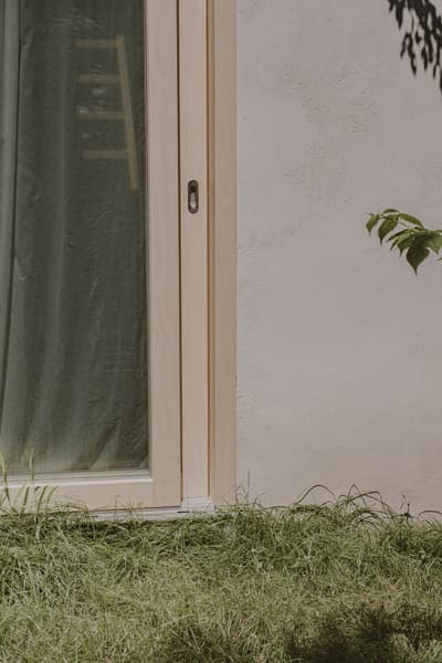 Architectural project - zen garden, grass lawn, wood, timber, outdoor space, timber frame, natural light, passive design, warm tones, green, neutral tones, beige, sunlight, simple design, organic design, serene atmosphere, calming space, minimalist design, eco-friendly materials, biophilic design, eco home, harmonious design, cozy vibe, textured wall, plaster wall, plaster, green living, landscape design, exterior view, garden view, sustainable facade, earthy textures, seamless transition, soft tones, modern exterior, natural insulation, sustainable living, sliding door, connection to nature, indoor outdoor flow, tranquility, wooden door