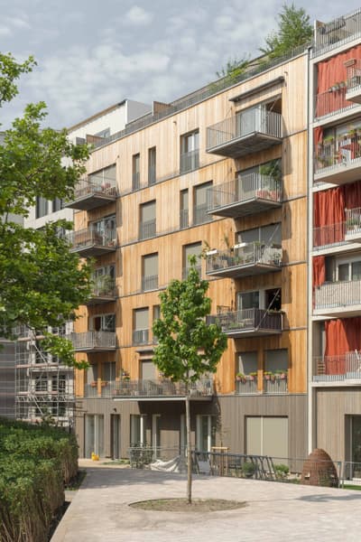 Architectural project - urban greenery, apartment facade, vertical elements, multi-story building, green facade, city apartment, community living, eco-conscious living, vertical design, natural materials, wood, timber, steel, metal, cityscape, outdoor living, passive design, sustainable design, warm tones, urban landscape, grey, daylight, beige, exterior design, light wood, urban oasis, sunlight, honey wood, urban design, timber cladding, wood cladding, modern architecture, earthy tones, environmental design, eco-friendly building, green design, wooden facade, inviting exterior, urban nature, low carbon building, modern exterior, architectural rhythm, architectural contrast, residential facade, urban living, contemporary building, open balconies