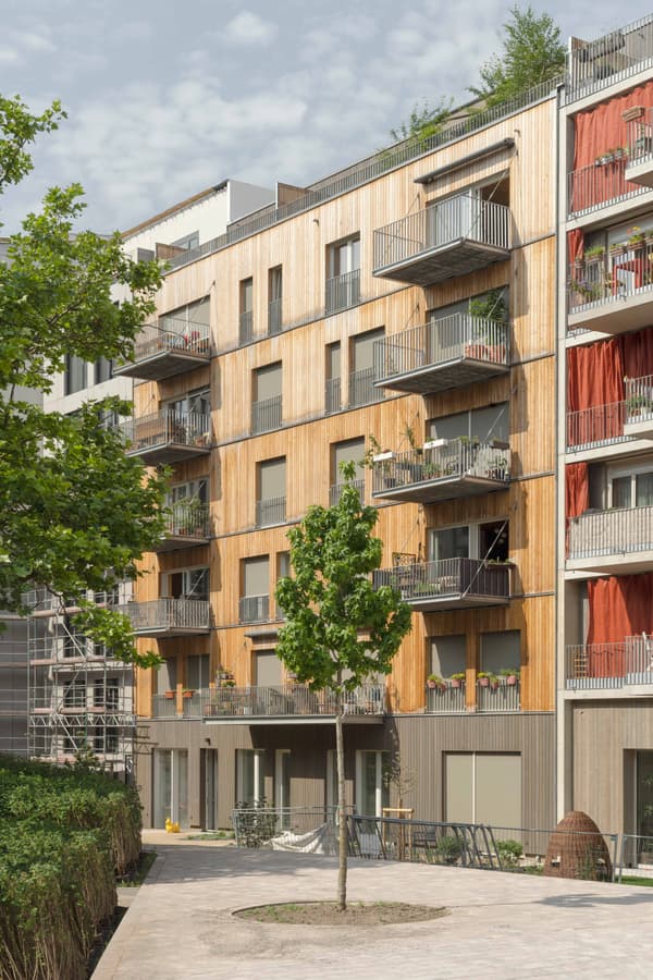 Architectural project - urban greenery, apartment facade, vertical elements, multi-story building, green facade, city apartment, community living, eco-conscious living, vertical design, natural materials, wood, timber, steel, metal, cityscape, outdoor living, passive design, sustainable design, warm tones, urban landscape, grey, daylight, beige, exterior design, light wood, urban oasis, sunlight, honey wood, urban design, timber cladding, wood cladding, modern architecture, earthy tones, environmental design, eco-friendly building, green design, wooden facade, inviting exterior, urban nature, low carbon building, modern exterior, architectural rhythm, architectural contrast, residential facade, urban living, contemporary building, open balconies
