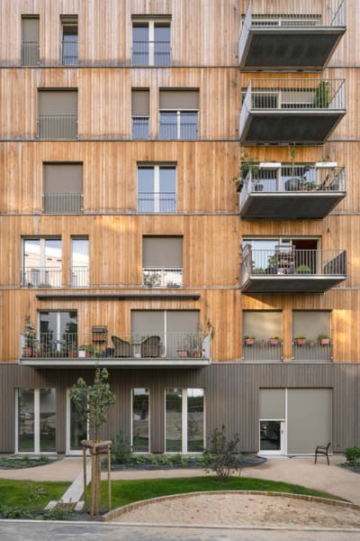 Architectural project - urban greenery, apartment facade, beige facade, potted plants, minimal style, green elements, exterior architecture, community living, natural materials, wood, timber, steel, cityscape, outdoor space, passive design, sustainable design, glass, natural tones, green building, neutral tones, beige, wood facade, timber facade, light wood, daylight optimization, urban oasis, timber construction, natural textures, contemporary design, timber cladding, wood cladding, modern architecture, energy efficient, exterior view, eco-friendly building, raw finish, eco architecture, warm exterior, urban nature, vertical cladding, facade rhythm, residential block, city dwelling, urban living, modern residential, open balconies