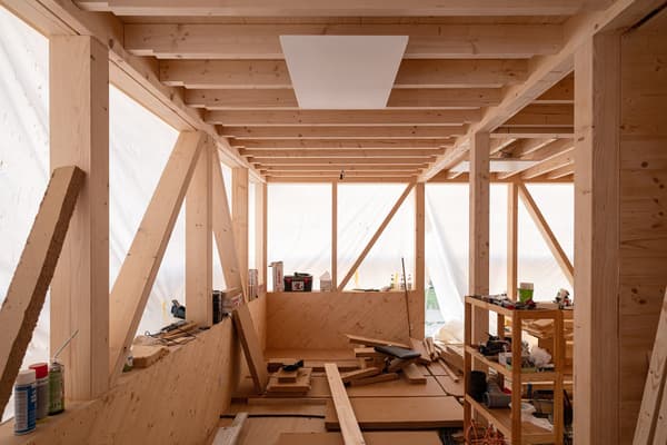 Architectural project - indoor space, natural materials, wood, timber, utilitarian design, timber frame, natural light, warm tones, modular design, exposed structure, sustainable architecture, construction phase, exposed beams, structural timber, construction site, work in progress, modern construction, daylight, plywood, construction process, building site, beige, light wood, open structure, wooden beams, timber construction, timber beams, light brown, carpentry work, raw wood, minimalist structure, industrial chic, wood structure, unfinished interior, plywood panels, timber panels, framing, sustainable building, eco construction, warm wood, rugged interior, skeletal structure, contemporary build, workshop area, wood frame structure, material assembly, timber walls, plywood wall, bare wood, frameless, rectangular forms, workspace