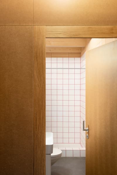 Architectural project - plywood walls, subtle design, cozy bathroom, small bathroom, home bathroom, residential bathroom, smooth surface, grid pattern, minimalist bathroom, compact bathroom, geometric tiles, intimate space, natural materials, architectural detail, timber, wooden frame, timber frame, sustainable design, warm tones, neutral tones, functional space, plywood, beige, brown, light wood, natural wood, functional design, eco friendly, simple design, honey wood, contemporary design, eco materials, clean lines, white, earthy tones, warm atmosphere, minimalist space, modern home, wooden texture, sleek design, practical space, timeless design, interior space, modern bathroom, eco bathroom, white tiles, tiled wall, ceramic tiles, timber door, wooden door, red