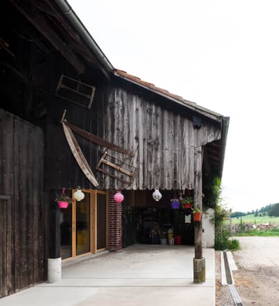 Architectural project - rural, farm building, barn renovation, timber texture, barn house, hanging plants, aged timber, farm life, barnyard, outdoor plants, natural materials, wood, timber, outdoor living, eco design, exposed structure, sustainable architecture, grey, beige, brown, concrete, timber facade, rural architecture, weathered wood, rustic charm, industrial touch, stone, open plan, wood texture, earthy tones, brick, rural setting, countryside, rustic barn, country vibe, rural vibe, wooden facade, timber exterior, countryside retreat, gravel path, pastoral scene, concrete floor, open space, wooden exterior, farm style, natural