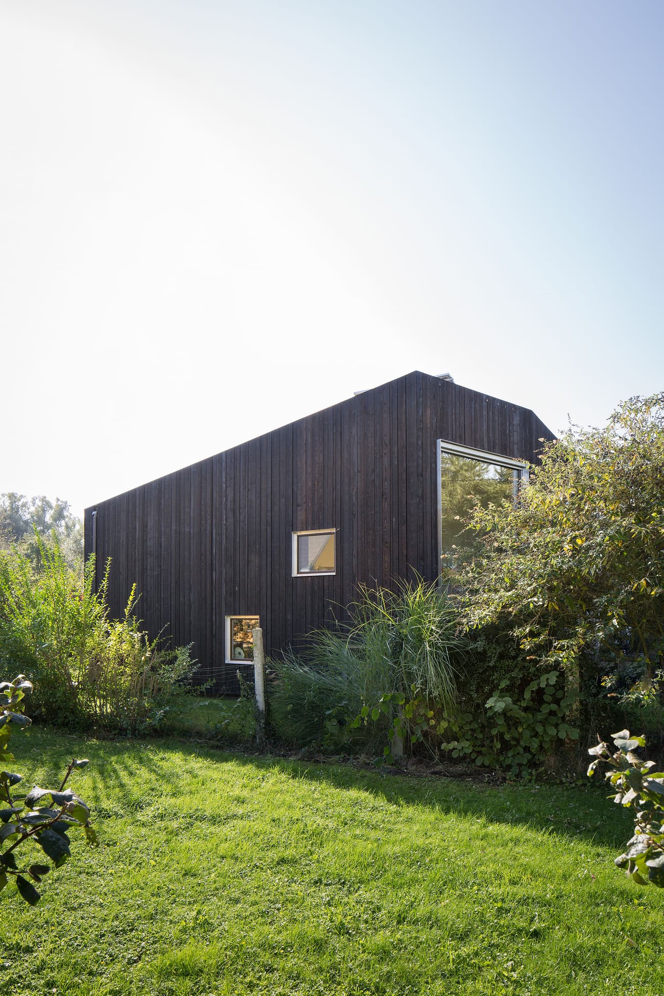 Architectural project - wood, timber, outdoor space, natural light, sustainable design, natural tones, contemporary style, sustainable architecture, green, brown, daylight optimization, minimalist design, black, eco materials, low carbon, biophilic design, passive house, scenic view, landscape integration, clean lines, timber cladding, eco friendly home, modern architecture, countryside home, large window, compact design, woodland setting, residential design, natural environment, garden view, secluded retreat, wooden facade, green lawn, modern cabin, black timber house, simple shape, geometric, small windows, private dwelling, dark tones, efficient design