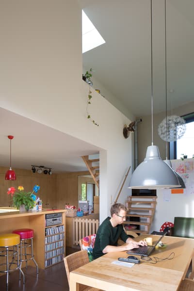 Architectural project - natural light, pastel colors, warm tones, multifunctional area, neutral tones, daylight, beige, brown, timber detail, eco friendly, compact space, Scandinavian style, creative space, white walls, cozy vibe, inviting home, wood accents, cozy nook, warm ambiance, casual living, open layout, open plan, family space, dining area, wooden table, dining table, residential design, comfortable seating, home office, bright interior, modern home, nordic influence, kid friendly, sustainable living, wood paneling, skylight, pendant lamp, work desk, indoor plants, colorful stools, playful details, staircase, relaxed home, minimalistic style, contemporary living, modern touches, vibrant home